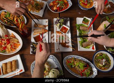 Des personnes non reconnaissables avec un bâton de choppon aux couleurs variées Une cuisine thaïlandaise épicée est servie pour un dîner en famille sur une table en bois Banque D'Images