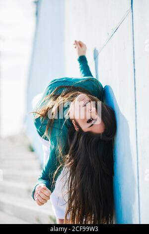 Vue latérale sur toute la longueur d'un jeune modèle féminin pieds nus à la caméra posé sur les escaliers près du mur bleu avec rouille tuyau métallique Banque D'Images