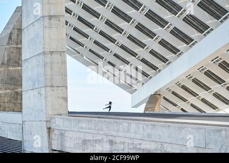 De dessous de la personne anonyme dansant sur la haute élévation contemporaine bâtiment en béton Banque D'Images