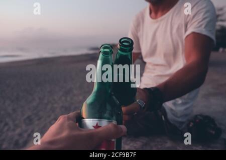 Des amis qui toaster avec de la bière sur la plage au coucher du soleil Banque D'Images