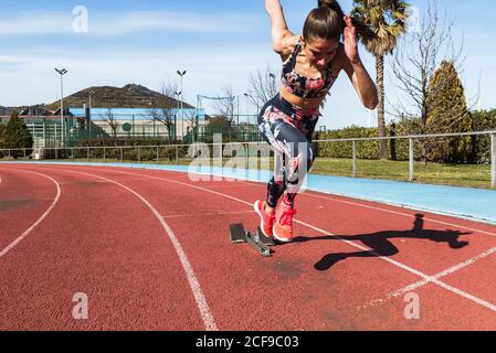 Forte athlète féminine dans les vêtements de sport course rapide contre le ciel bleu par beau temps dans le stade Banque D'Images