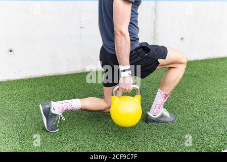 Vue latérale de la récolte jeune sportif homme qui lance un entraînement intensif balle près du pneu et du mur gris Banque D'Images