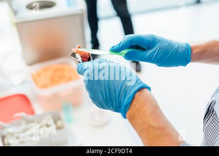 Du dessus de la récolte les mains d'étudiant mâle tenant la prothèse et la pâte assis à la table pendant le cours de dentisterie Banque D'Images