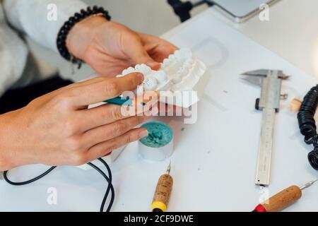 De dessus de la récolte orthodontiste avec un crayon dans la main de travail avec moule dentaire blanc à la table avec équipement professionnel Banque D'Images