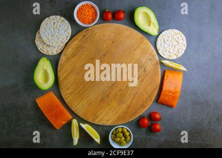 Saumon cru aux épices et aux légumes autour de planches rondes en bois sur la table en graphite. Vue de dessus avec espace libre Banque D'Images