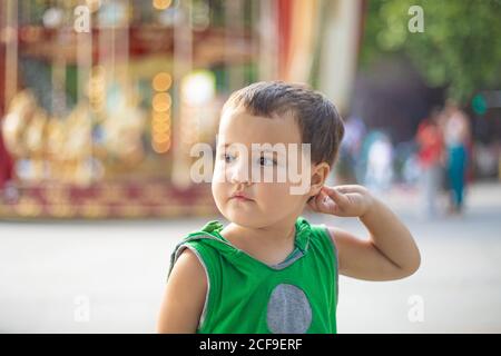 Enfant se tenant près du carrousel en mouvement et rêvant à la foire Banque D'Images