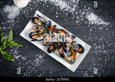 Moules cuites à la vapeur avec sauce thaï dans une assiette blanche Banque D'Images