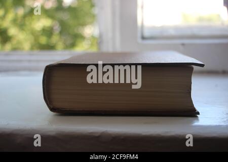 Livre fermé sur la table devant la fenêtre. Concept d'éducation Banque D'Images