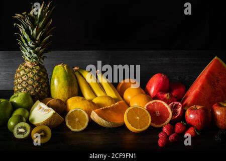 Bouquet de divers fruits frais pleins de vitamines placées dessus table de bois noire Banque D'Images