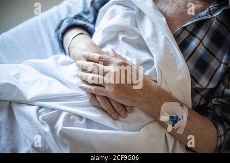 Du dessus de la récolte patient âgé avec cathéter intraveineux dans le bras couché sous une couverture et dormant Banque D'Images