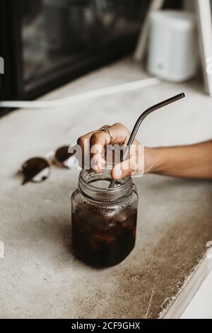 Femme écourtée non reconnaissable tenant main un verre de cocktail sur un comptoir en béton Banque D'Images