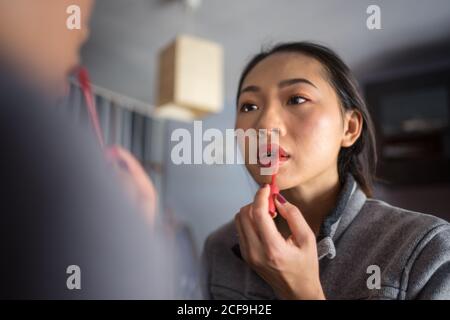 Jeune femme appliquant le rouge à lèvres devant le miroir Banque D'Images