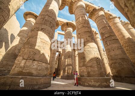 Le Caire, Egypte - 14 décembre 2019: Touriste avec téléphone photographiant d'énormes piliers anciens au temple de Karnak sculpté avec hiéroglyphes Banque D'Images