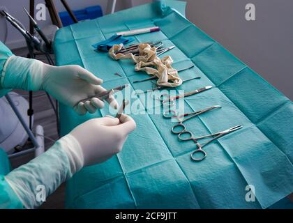 Par-dessus l'infirmière sans visage dans les gants en caoutchouc choisir les outils pour le chirurgien de la table pendant l'opération à l'hôpital Banque D'Images