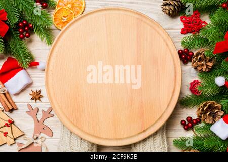 Vue de dessus de la main tenant une plaque sur fond de bois de vacances. Sapin et décorations de Noël. Nouvelle Année temps cocnept. Banque D'Images