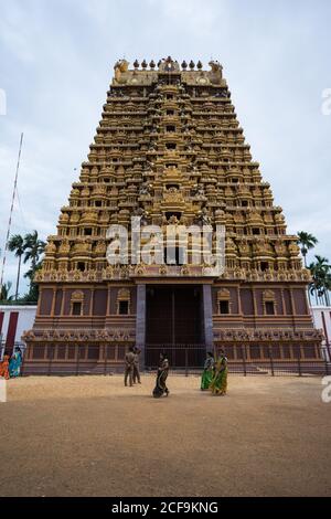 Jaffna, Sri Lanka - août 9 2019 : foule de Hindous vêtés de vêtements traditionnels qui marchent à l'extérieur d'une tour de neuf étages sculptée à l'ornée lors du festival du Kovil de Nallur Kandaswamy par temps nuageux Banque D'Images