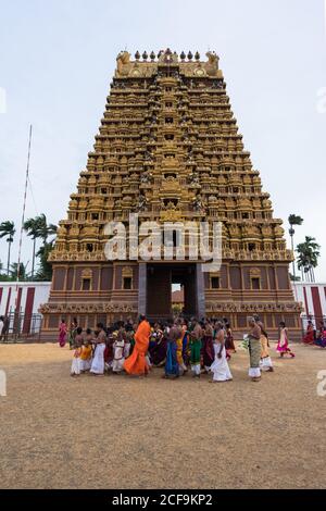 Jaffna, Sri Lanka - août, 7 2019: Groupe de personnes hindoues en vêtements traditionnels debout sur le sable près de la tour de gopuram du temple pendant le festival du Kovil de Nallur Kandaswamy Banque D'Images