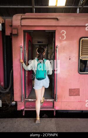 Vue arrière de la femme voyageur à cheveux noirs non reconnaissable dans une ambiance décontractée Porter un train à bord à la gare de Colombo à Sri Lanka Banque D'Images