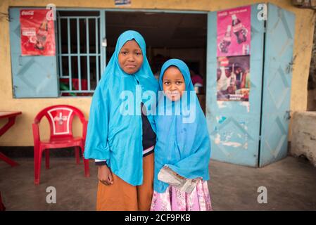 Tanzanie, Afrique de l'est - novembre, 2016: Les petites africaines femmes locales dans la tête musulmane bleue fougue sourire et regarder la caméra en Tanzanie Banque D'Images