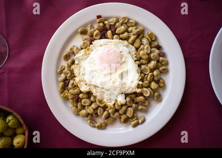 Du dessus du plat de haricots avec l'œuf frit servi Assiette sur nappe rouge dans le restaurant de Malaga Banque D'Images