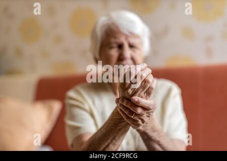 Femme senior avec arthrite frottant les mains Banque D'Images