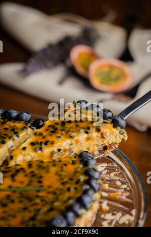 D'un morceau de tarte aux fruits de la passion appétissante avec garnitures de myrtille sur fond de bois Banque D'Images
