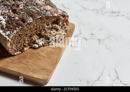 Vue de dessus de délicieux pain de seigle complet et sain sur pain planche à découper en bois sur table en marbre Banque D'Images