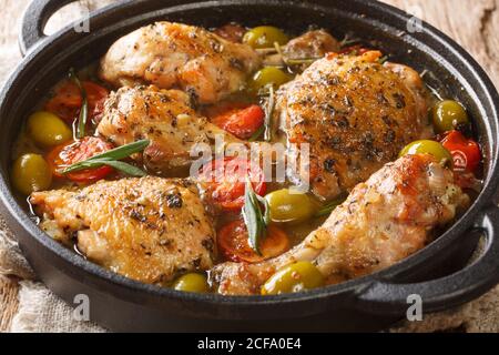 Délicieux poulet haché cuit avec des olives vertes, des tomates et des oignons, des herbes gros plan dans une poêle sur la table. Horizontal Banque D'Images