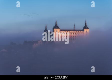 D'en haut merveilleux paysage de château médiéval construit au-dessus de la ville dans un lever de soleil coloré et brumeux Banque D'Images