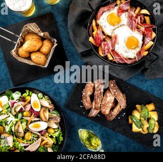 Vue de dessus de la cuisine espagnole typique, y compris des croquettes et du thon Salade et porc ibérique et œufs frits avec jambon servi sur la table Banque D'Images