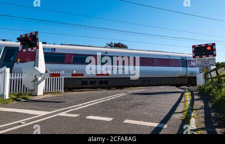 LNER Azuma train sur la ligne de chemin de fer principale de la côte est passage à niveau avec feux clignotants, Markle, East Lothian, Écosse, Royaume-Uni Banque D'Images