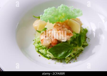 Délicieux risotto aux épinards, aux légumes verts et aux crevettes. Servi dans une vaisselle moderne. dof peu profond Banque D'Images