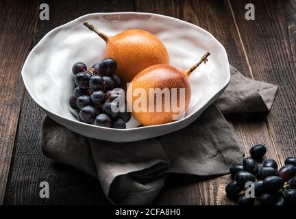 Fruits de la passion mûrs et petits pains de raisins violets placés dessus table en bois dans la cuisine Banque D'Images