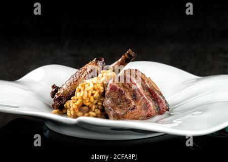 Délicieux riz bouilli avec viande de poulet grillée sur céramique blanche assiette sur fond sombre flou dans un restaurant moderne Banque D'Images