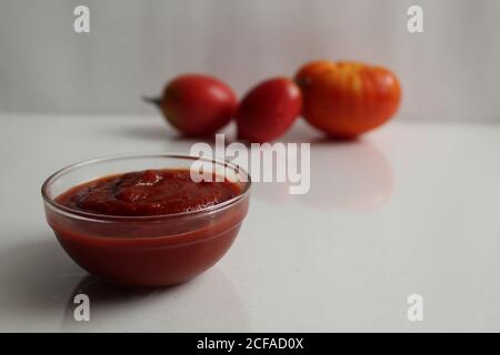 ketchup à la sauce tomate rouge dans une casserole en verre sur un fond blanc sont les légumes dans le fond rouge tomates Banque D'Images