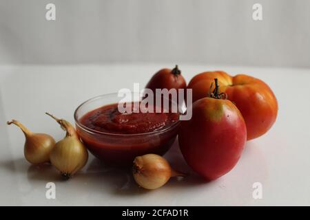 ketchup à la sauce tomate rouge dans une casserole en verre sur un fond blanc sont les légumes dans le fond rouge tomates Banque D'Images