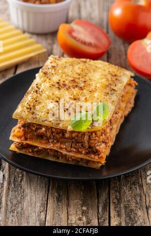 Morceau de lasagne à la viande sur une assiette noire sur une table en bois Banque D'Images