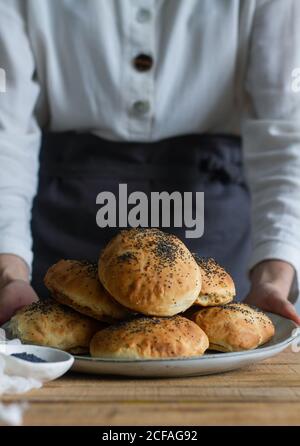 plat de cuisson non reconnaissable avec petits pains délicieux et graines de pavot sur une table en bois dans la boulangerie Banque D'Images