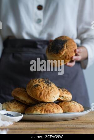 plat de cuisson non reconnaissable avec petits pains délicieux et graines de pavot sur une table en bois dans la boulangerie Banque D'Images