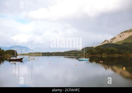 Paysage pittoresque de montagne et ciel nuageux se reflète dans la tranquillité De l'eau avec des voiliers à Glencoe pendant la journée Banque D'Images