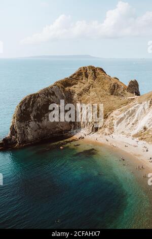 Depuis le haut paysage idyllique de mer avec des rochers appelés Durdle Door et les gens se détendent sur la mer le jour de l'été Banque D'Images