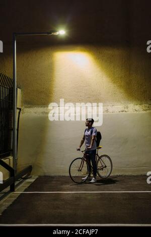 Vue de face d'un homme prenant un vélo d'un parking la nuit pour rentrer à la maison Banque D'Images