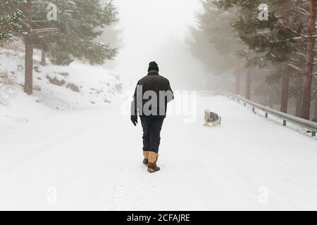 homme âgé méconnu et son chien marchant dans la neige avec brouillard Banque D'Images