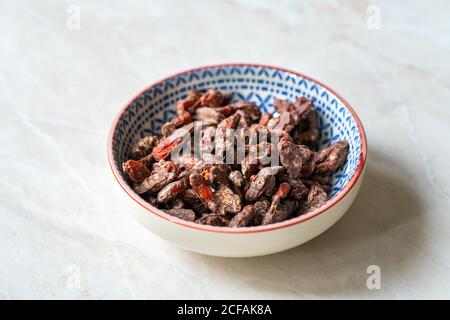Baies de Goji / baies enrobées de chocolat amer. En-cas biologiques et crus sains de Wolfberry. Prêt à manger. Banque D'Images