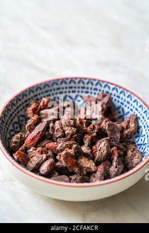 Baies de Goji / baies enrobées de chocolat amer. En-cas biologiques et crus sains de Wolfberry. Prêt à manger. Banque D'Images