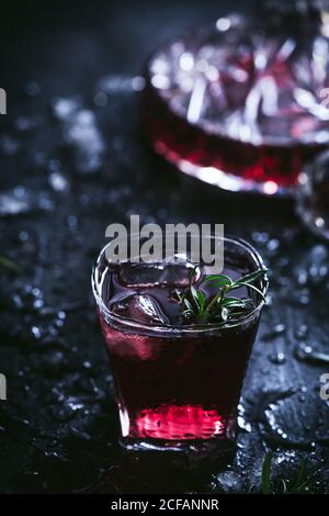Carafe et verres en cristal avec glace remplie de vin rouge sur table noire Banque D'Images