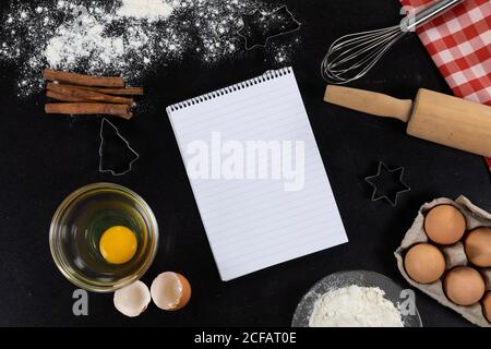 Vue d'une page de bloc-notes vide avec des ingrédients préparés pour cuire des biscuits, disposés sur une feuille ordinaire Banque D'Images