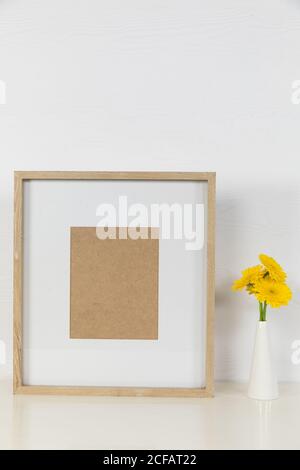 Vue d'un cadre photo, avec des tulipes jaunes placées dans un vase en verre sur fond blanc Uni Banque D'Images