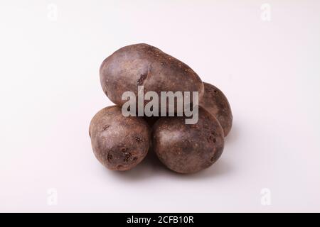 Pommes de terre violettes sur fond blanc. Banque D'Images