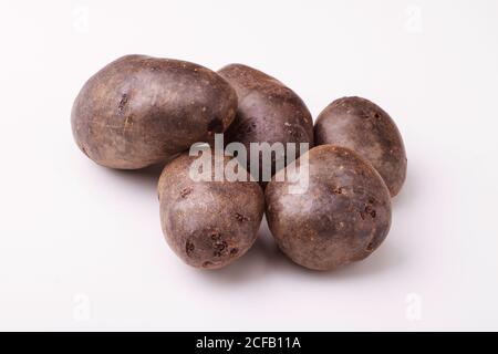 Pommes de terre violettes sur fond blanc. Banque D'Images